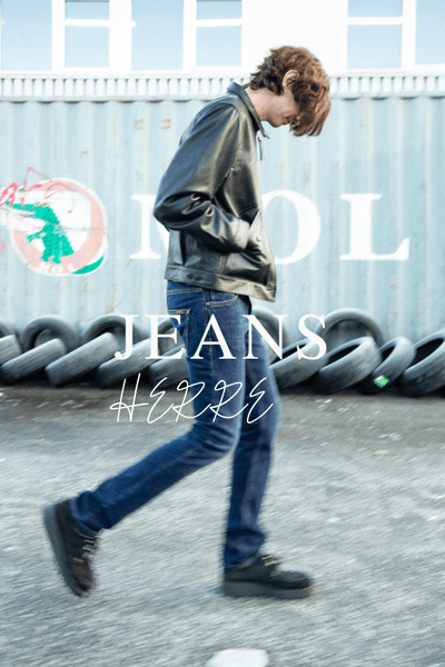 Herrejeans fra Nudie i mørk denim, modell gående utendørs